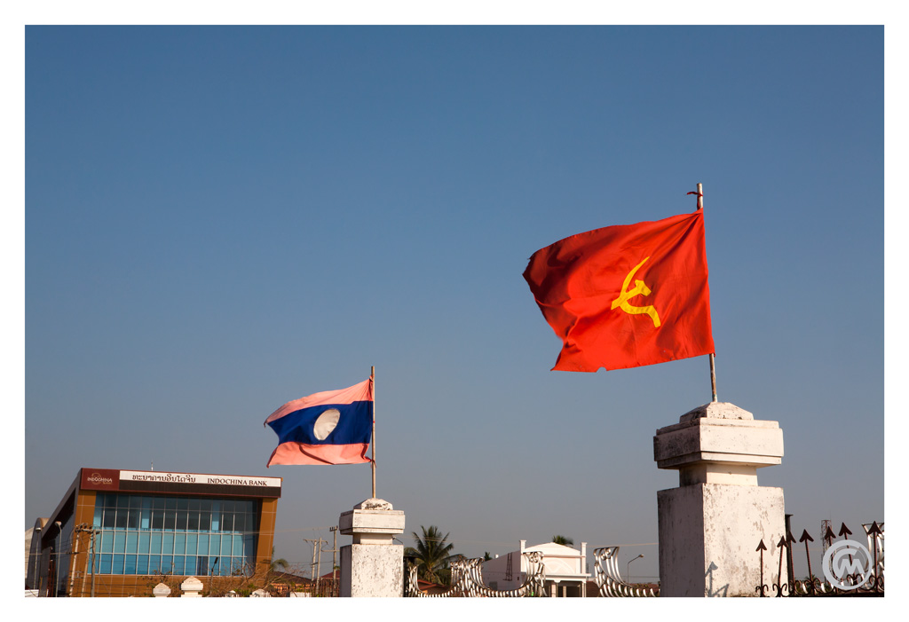 Laos and communist flags in from of the Indochina Bank in Pakse, Laos